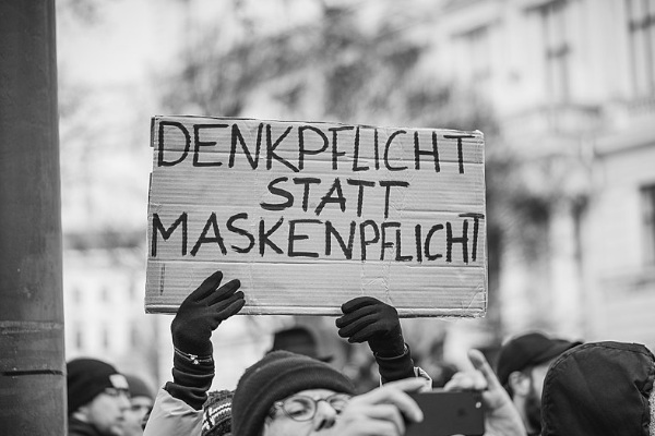 Bild von Corona-Demo. Demonstrant hält Schild hoch, auf dem steht: Denkpflicht statt Maskenpflicht.